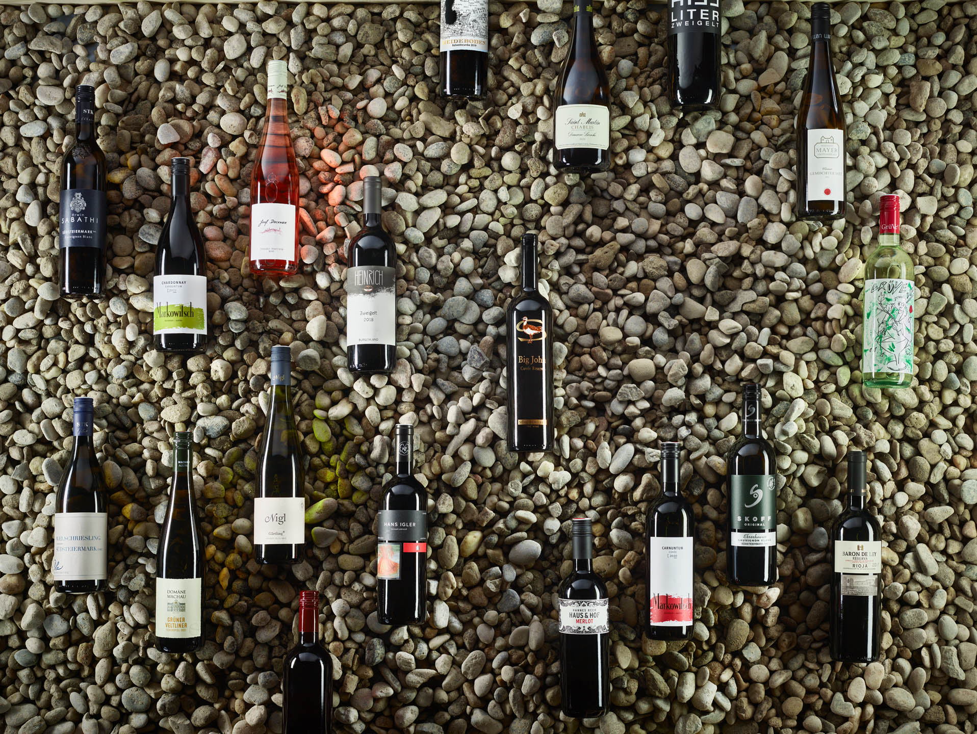 viele Weinflaschen auf Steinuntergrund liegend fotografiert